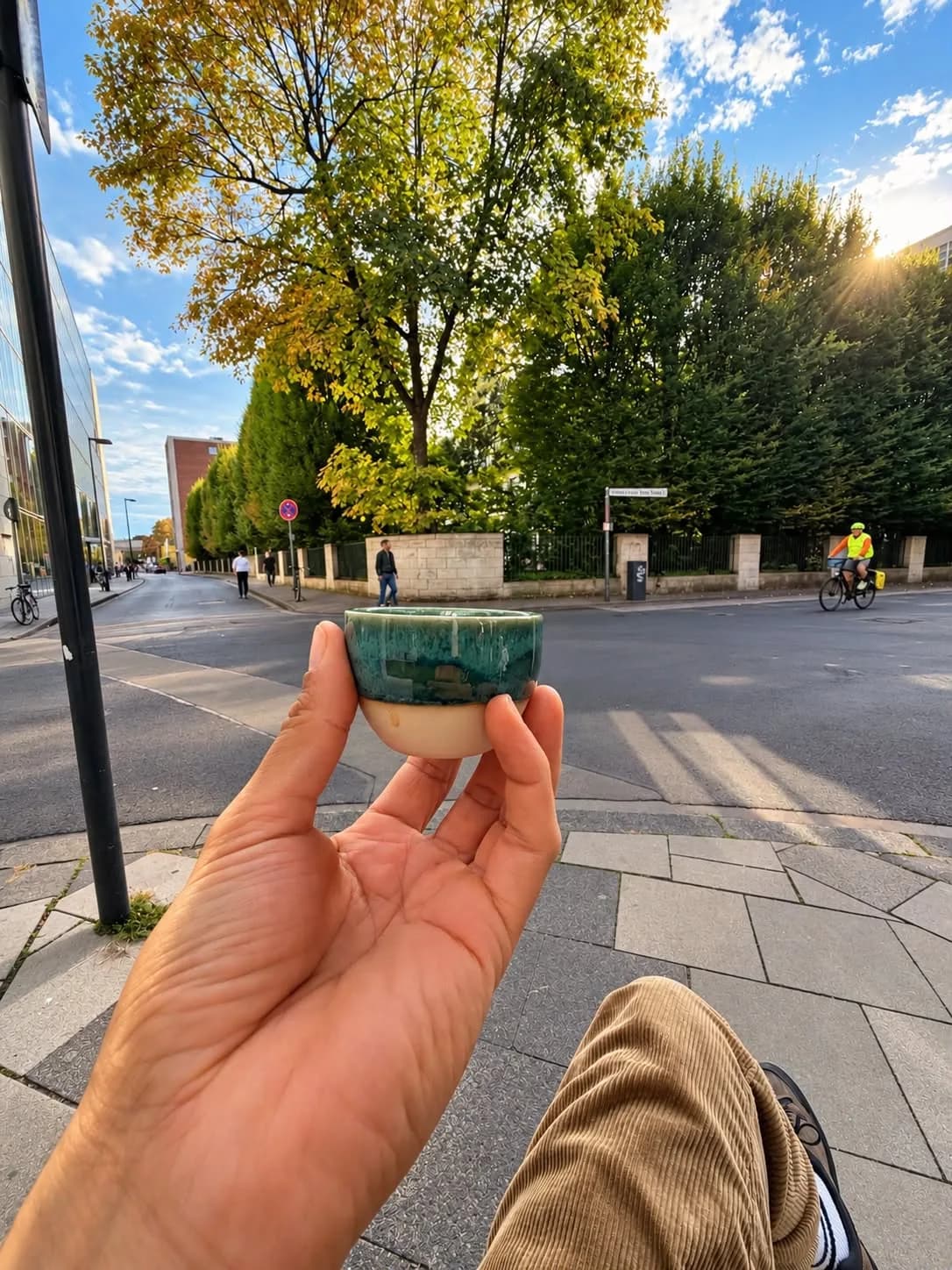 Keramiktasse in der Hand, im Hintergrund die Kölner Straße